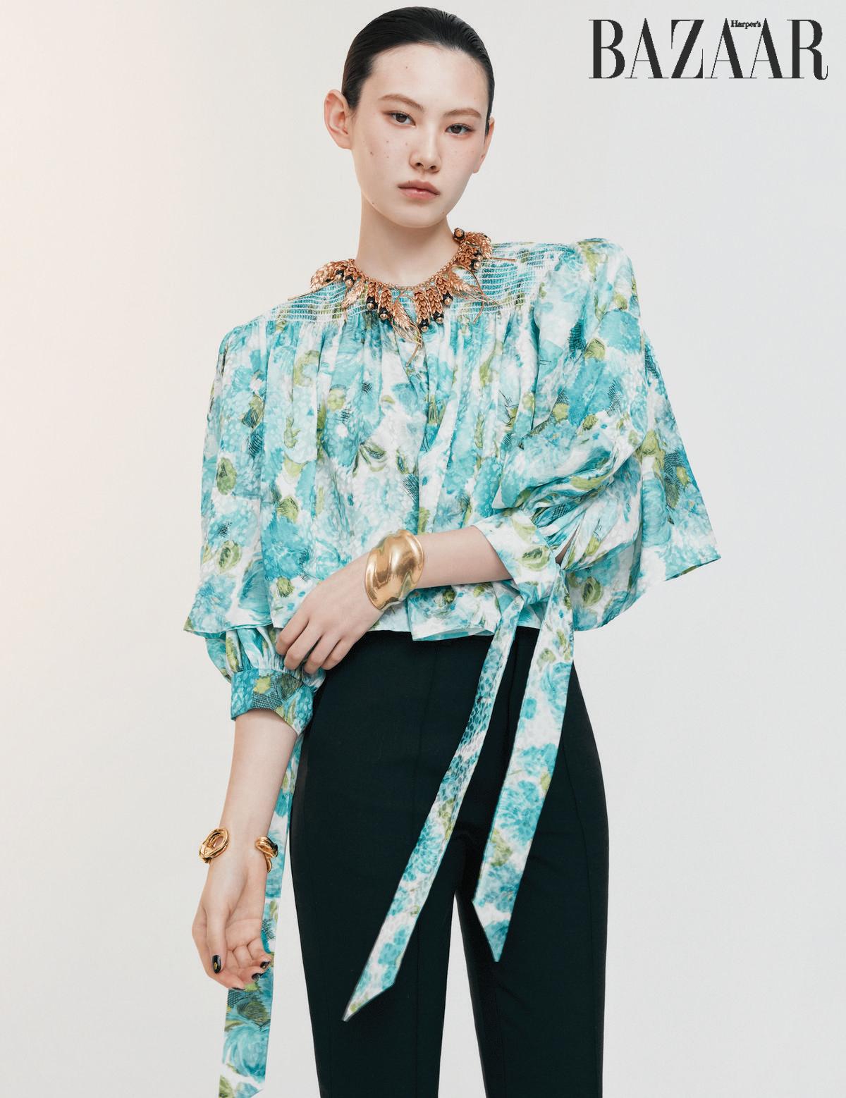 플라워 프린트 블라우스는 Chloé. 팬츠는 Celine. 초커는 Chanel. 양팔에 착용한 뱅글은 Saint Laurent by Anthony Vaccarello.